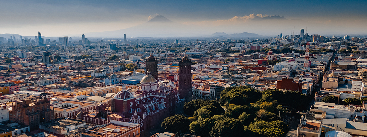 Luftaufnahme von Puebla mit dem Popocatepetl Vulkan im Hintergrund.