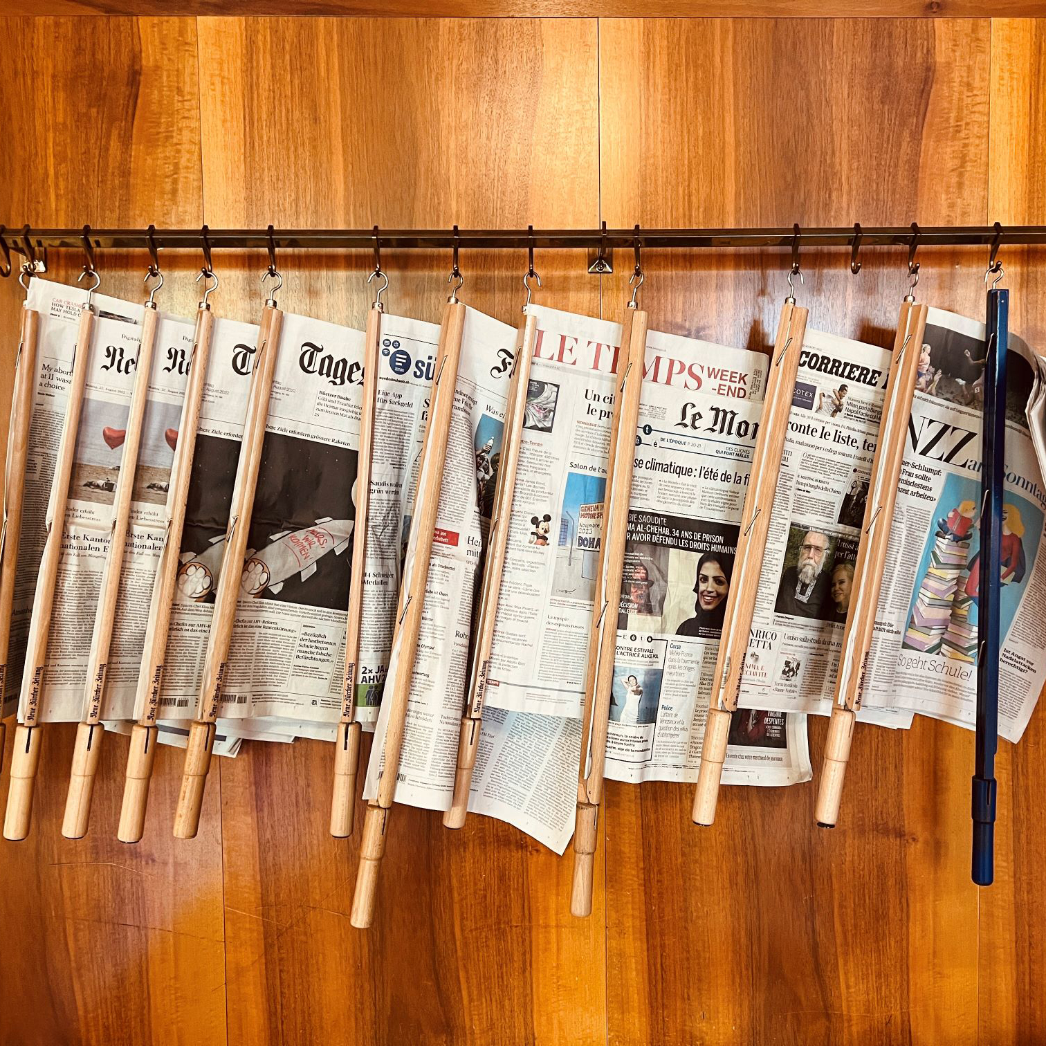 Holzstange, an der verschiedene Zeitungen hängen.